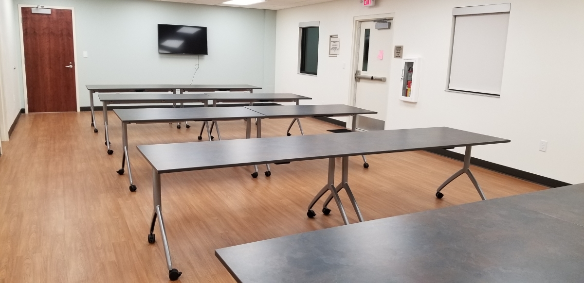 Larger meeting room with tables and chairs. TV access for presentations. Access to the kitchen. 